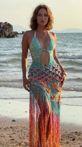 Woman wearing turquoise sequin crochet halter cutout maxi dress with ombre fringe on a beach front view