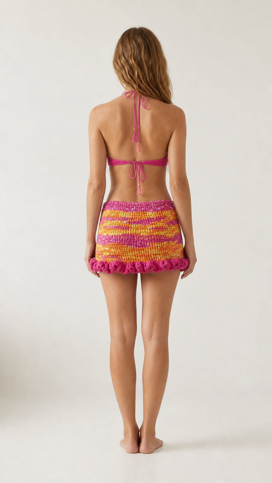 Back view of model wearing Fuchsia Multi crochet halter top with tie-back closure and mini skirt