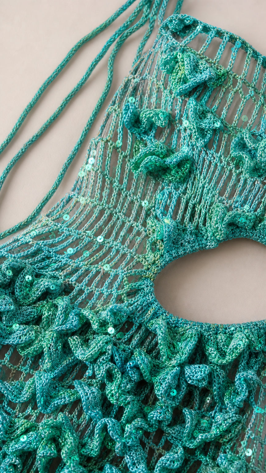 Close-up detail of teal green sequined knit fabric and 3D rosette crochet embellishments